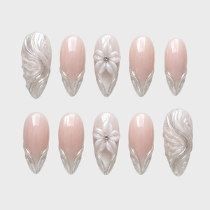 A set of nude press-on nails featuring 3D white flowers and metallic silver swirl designs.