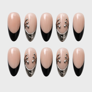 Nude and black French tip press-on nails with silver metallic scroll embellishments.