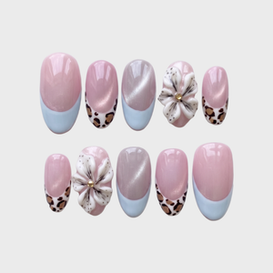 Pink cat-eye press-on nails with blue French tips, leopard print accents, and 3D white flowers.