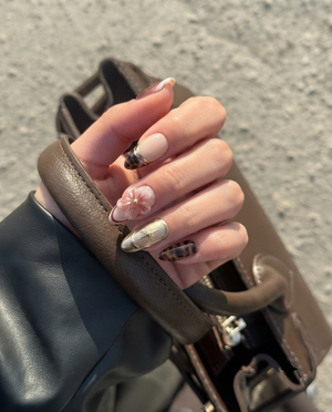 A set of press-on nails featuring 3D floral designs, tortoise shell patterns, and burgundy ombre with pearl accents.