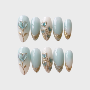 Mint blue and milky white ombr������������ press-on nails with 3D heart-shaped floral details and metallic gold accents.