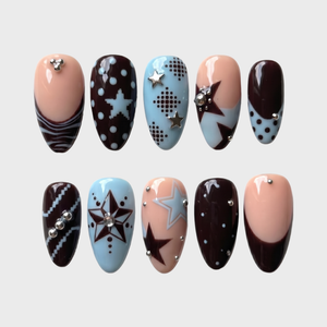 A set of press-on nails featuring mocha brown, baby blue, and nude colors with star and dot motifs and silver studs.