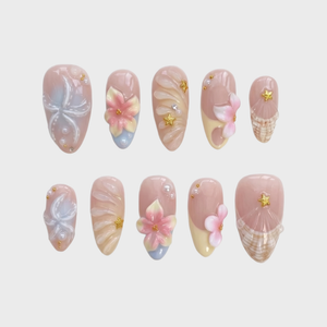 A set of pink press-on nails featuring 3D flowers, starfish, seashells, pearls, and gold star details.