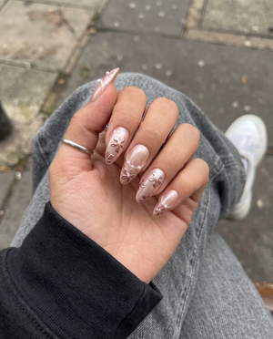 Rose gold press-on nails with 3D metallic floral details, pearl accents, and a shimmery finish.