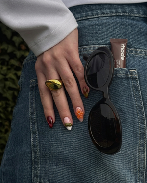 A set of press-on nails featuring burgundy cat-eye, tortoiseshell patterns, and 3D floral accents.
