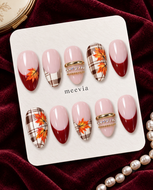 Pink and burgundy press-on nails with brown plaid, orange maple leaves, and gold accents