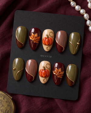 Autumn pumpkin and maple leaf press-on nails in glossy olive, burgundy, brown, mauve, and cream tones with gold accents