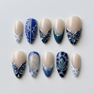A set of blue and white porcelain-style press-on nails featuring floral patterns, marble designs, and silver accents.