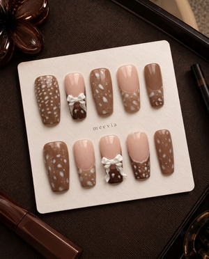 Brown and nude speckled press-on nails with raised white bow embellishments