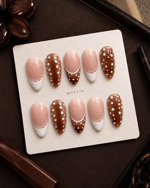 Brown and nude pink press-on nails with white polka dots, French tips, and scalloped accents