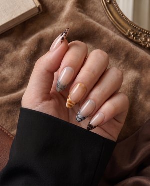 Sheer nude press-on nails with glossy brown, amber, and black snake-print French tips
