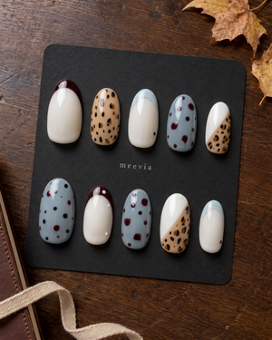 Glossy press-on nails with burgundy French tips, tan leopard print, creamy white bases, and blue dotted accents