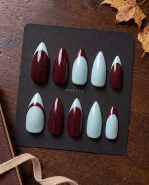 Burgundy and light blue glossy French tip press-on nails arranged on a black display board