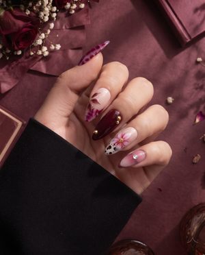 Burgundy and pink floral cow print press-on nails with glossy finish and gold embellishments