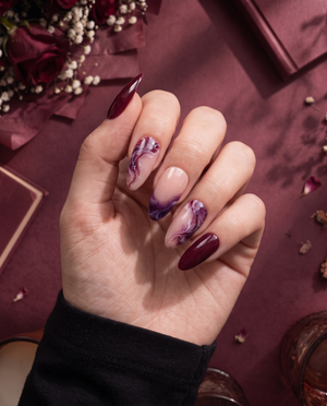 Burgundy and pink glossy marble press-on nails displayed on a white card