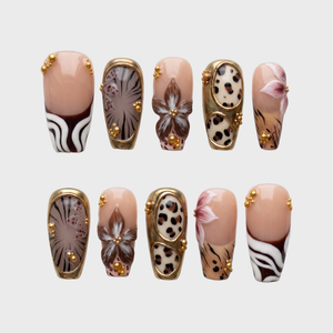 A set of safari-themed press-on nails featuring leopard print, zebra stripes, metallic gold borders, and gold bead embellishments.