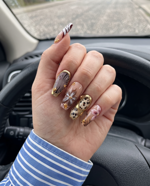 A set of safari-themed press-on nails featuring leopard print, zebra stripes, metallic gold borders, and gold bead embellishments.