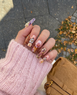 Set of almond-shaped press-on nails featuring pink and white colors, gold leopard print patterns, raised bows, and rhinestone embellishments.