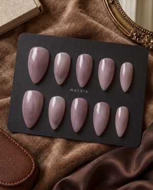 Glossy mauve taupe almond press-on nails displayed on a black nail card