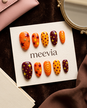 Orange and maroon celestial press-on nails with stars, dots, and swirl designs