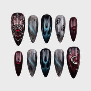A set of gothic-themed stiletto press-on nails featuring spider webs, ghosts, flames, and moon charms in burgundy and grey tones.