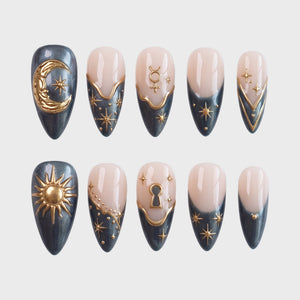 Celestial themed press-on nails in charcoal grey and nude with gold moon, sun, and star embellishments.