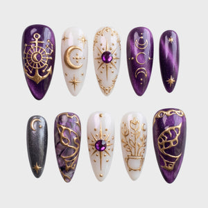 Set of celestial themed press-on nails in purple and white with gold moon and star accents.