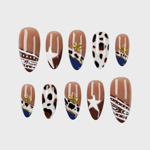 Set of press-on nails with brown, white, and navy patterns, cow print, and gold star details.