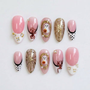 Halloween-themed press-on nails featuring ghost motifs, gold spider webs, and pink French tips.