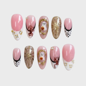 Halloween-themed press-on nails featuring ghost motifs, gold spider webs, and pink French tips.