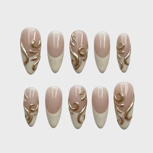Nude and white French tip press-on nails featuring raised gold metallic swirl designs.