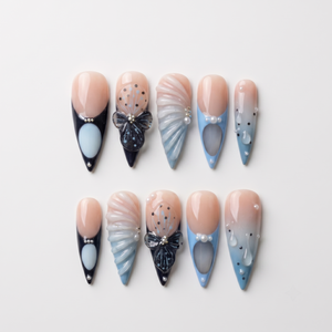 Set of stiletto press-on nails featuring blue and black French tips, butterfly art, pearl accents, and 3D shell textures.