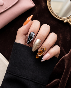 Tortoiseshell and abstract art press-on nails with pink, gold, orange, black, and white designs