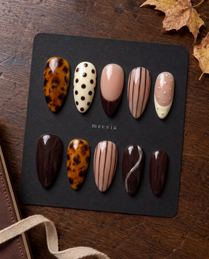 Brown tortoiseshell and striped press-on nails with glossy nude, ivory, and chocolate designs
