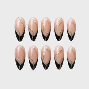 A set of nude and black French tip press-on nails accented with gold glitter swirls.