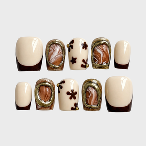 Brown marble accent French tip press-on nails with floral motifs and gold embellishments.