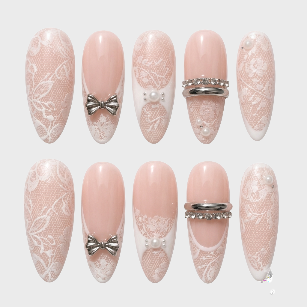 Stiletto press-on nails with nude base, white lace pattern, silver bows, and pearl accents.
