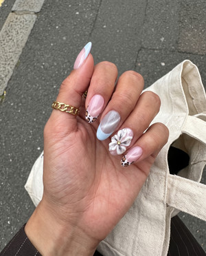 Pink cat-eye press-on nails with blue French tips, leopard print accents, and 3D white flowers.