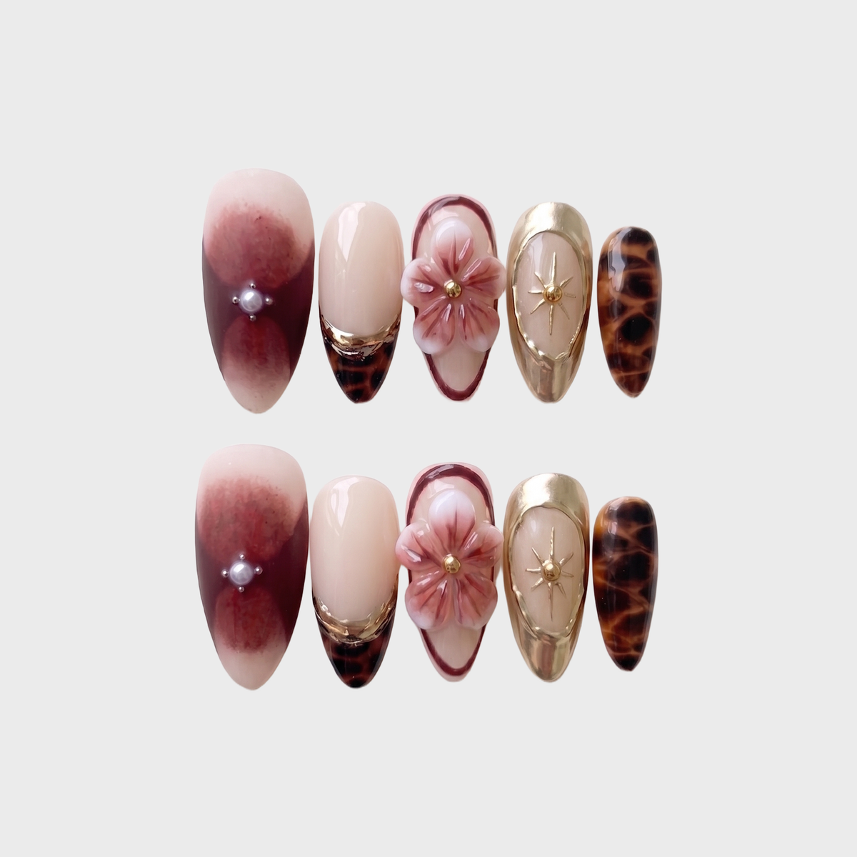 A set of press-on nails featuring 3D floral designs, tortoise shell patterns, and burgundy ombre with pearl accents.
