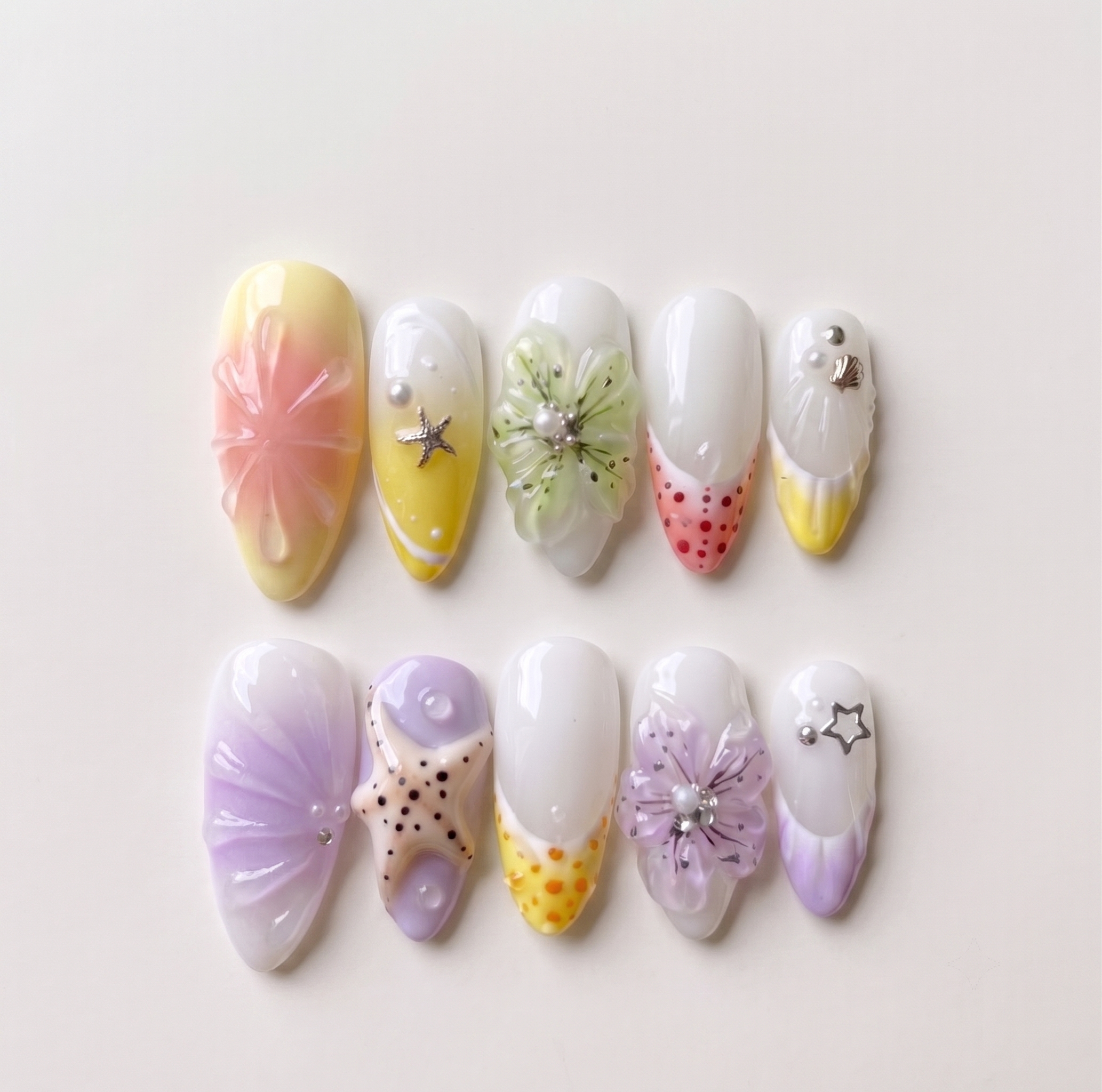 Pastel press-on nails featuring 3D flowers, starfish charms, ocean shells, and pearls.