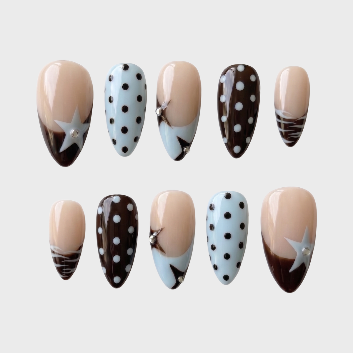 Glossy brown and light blue press-on nails with star motifs, polka dots, and rhinestone accents.
