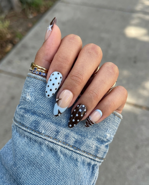 Glossy brown and light blue press-on nails with star motifs, polka dots, and rhinestone accents.