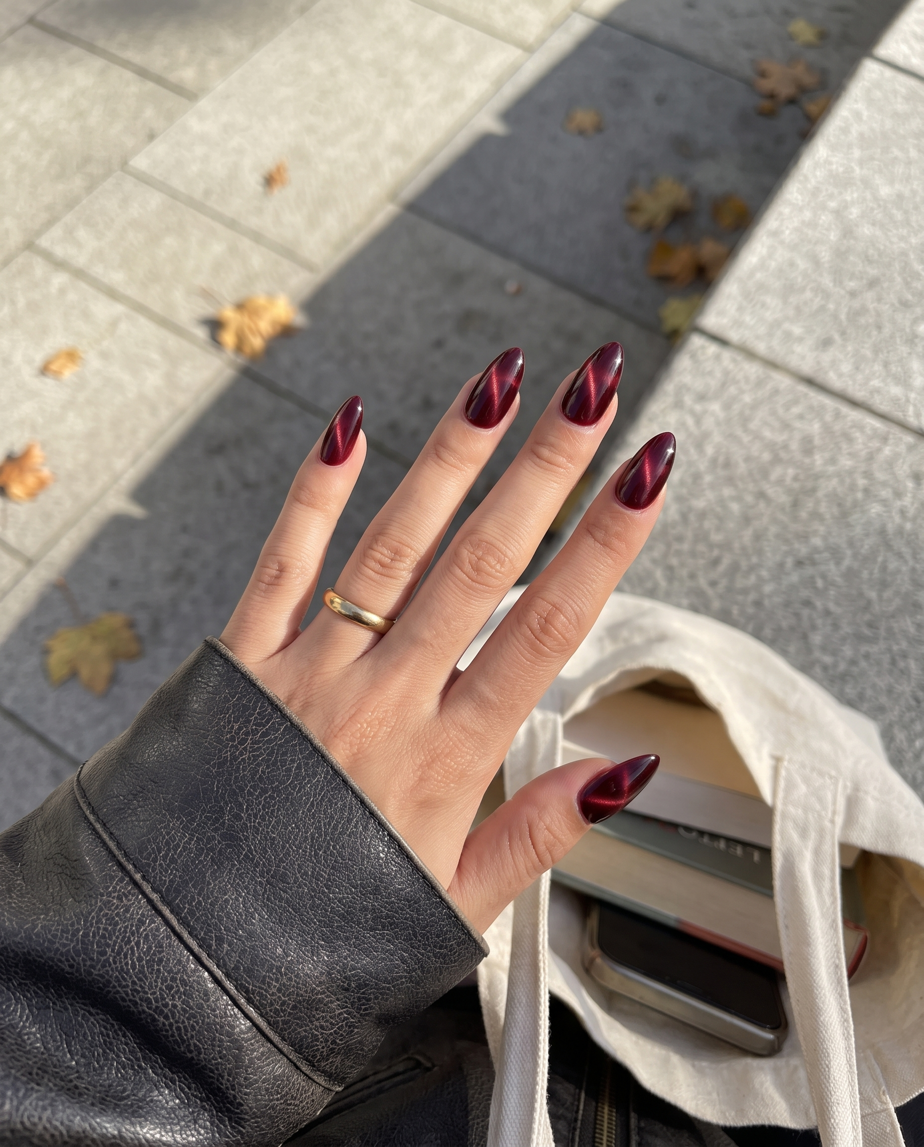 Ten almond-shaped press-on nails in a deep burgundy color with a magnetic cat eye shimmer effect.