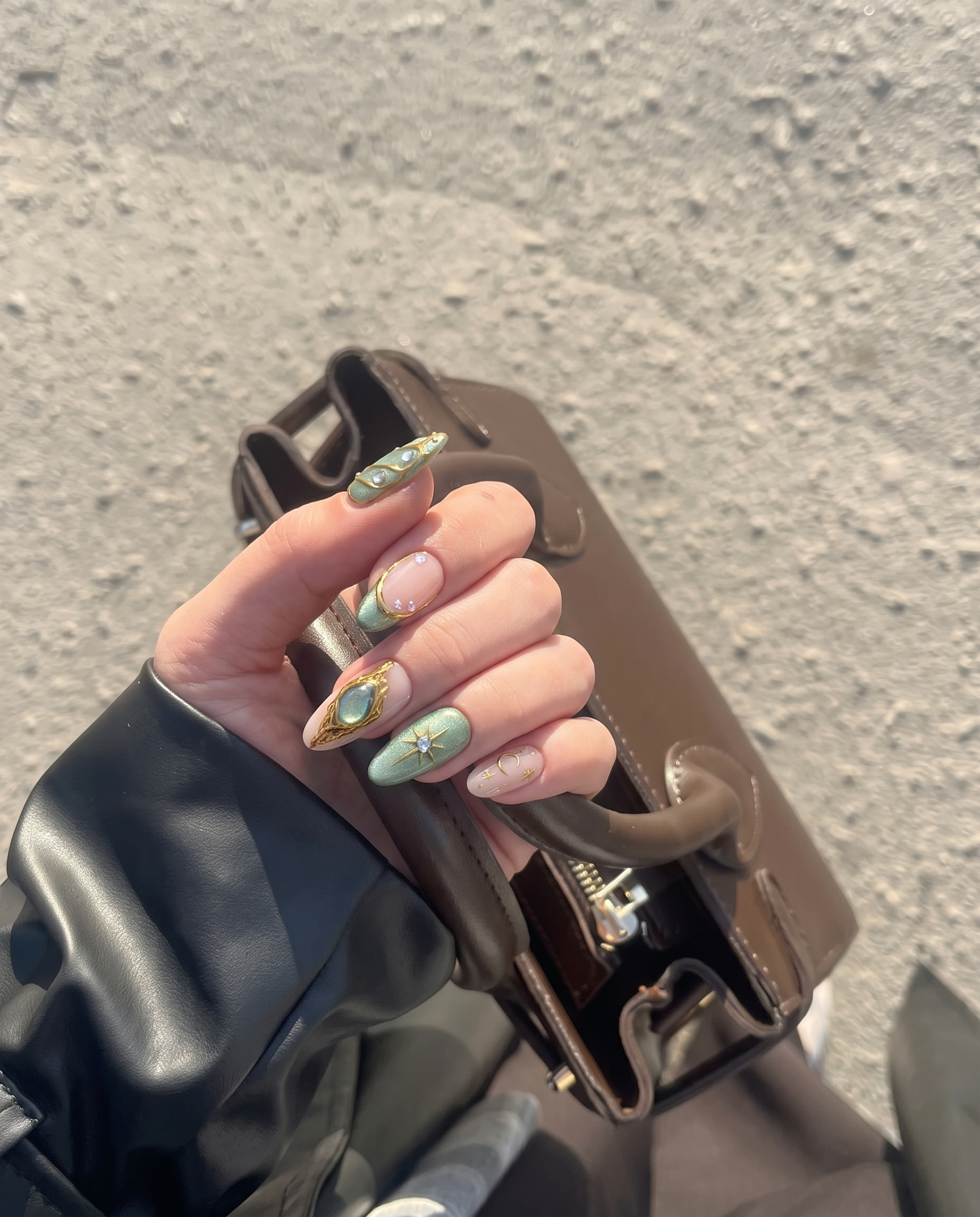 Sage green and pink press-on nails featuring gold celestial stars, crescent moons, butterfly wings, and rhinestone accents.