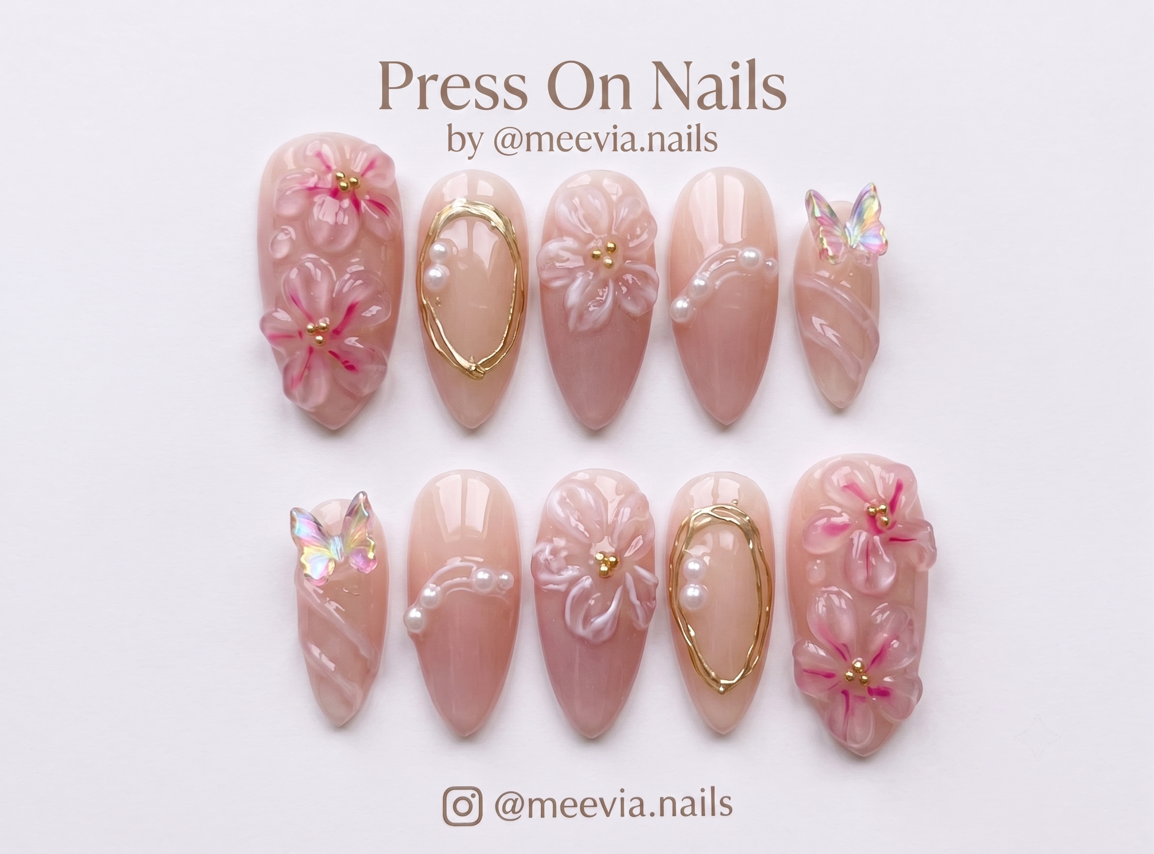 A set of pink press-on nails featuring 3D floral designs, iridescent butterfly charms, and gold wire accents.