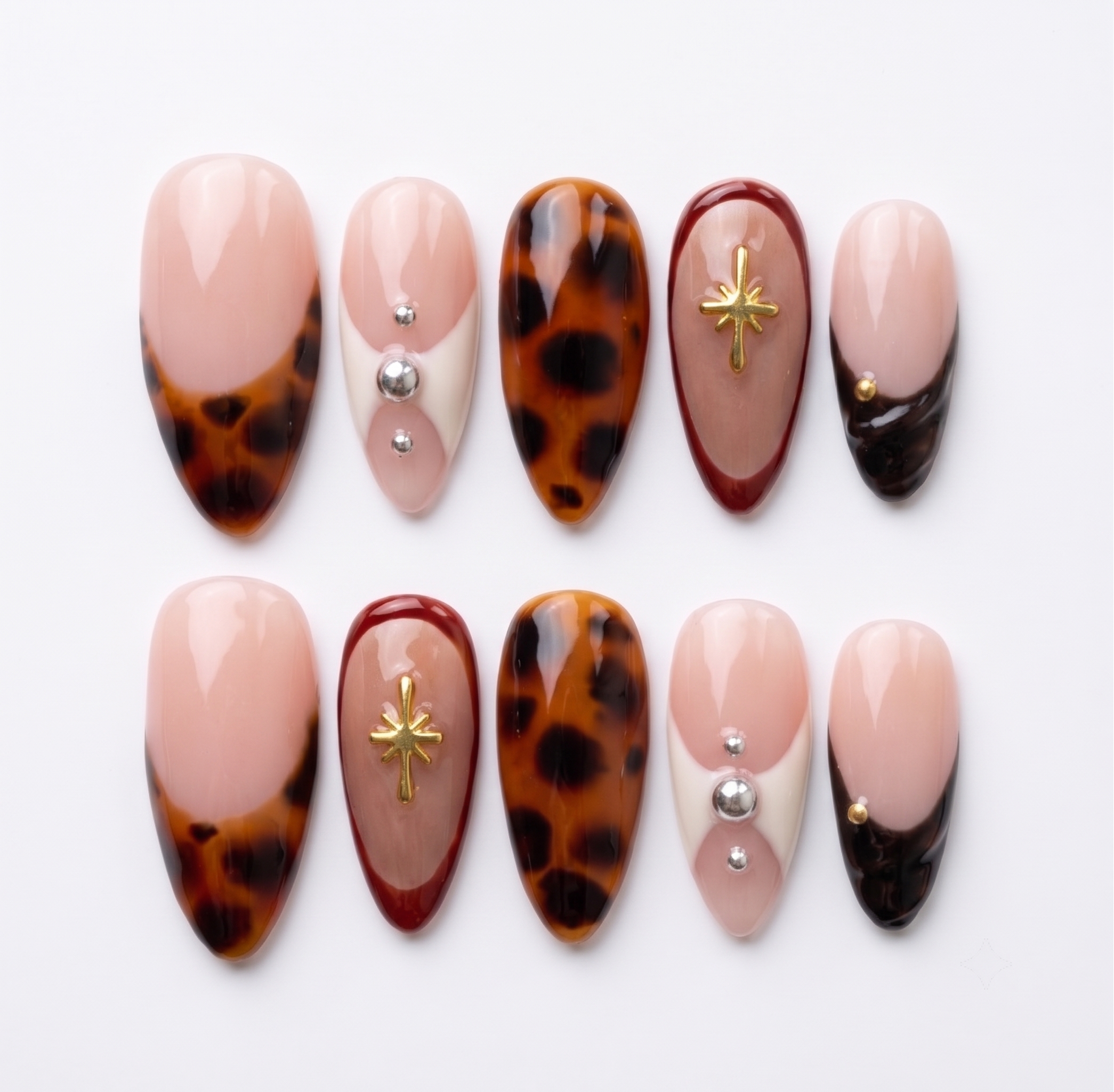 Tortoiseshell French tip press-on nails with gold star charms and silver studs.