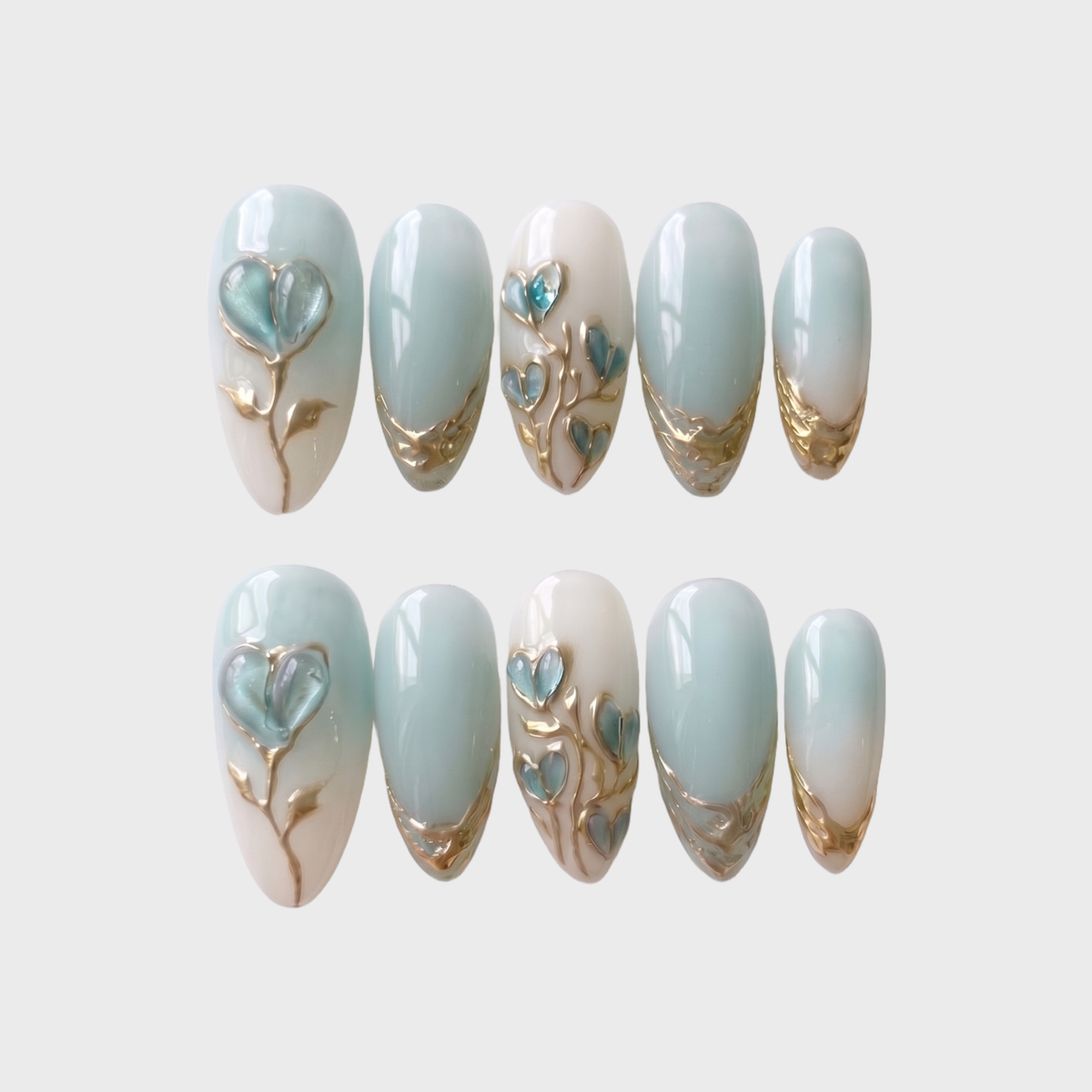 Mint blue and milky white ombr������������ press-on nails with 3D heart-shaped floral details and metallic gold accents.