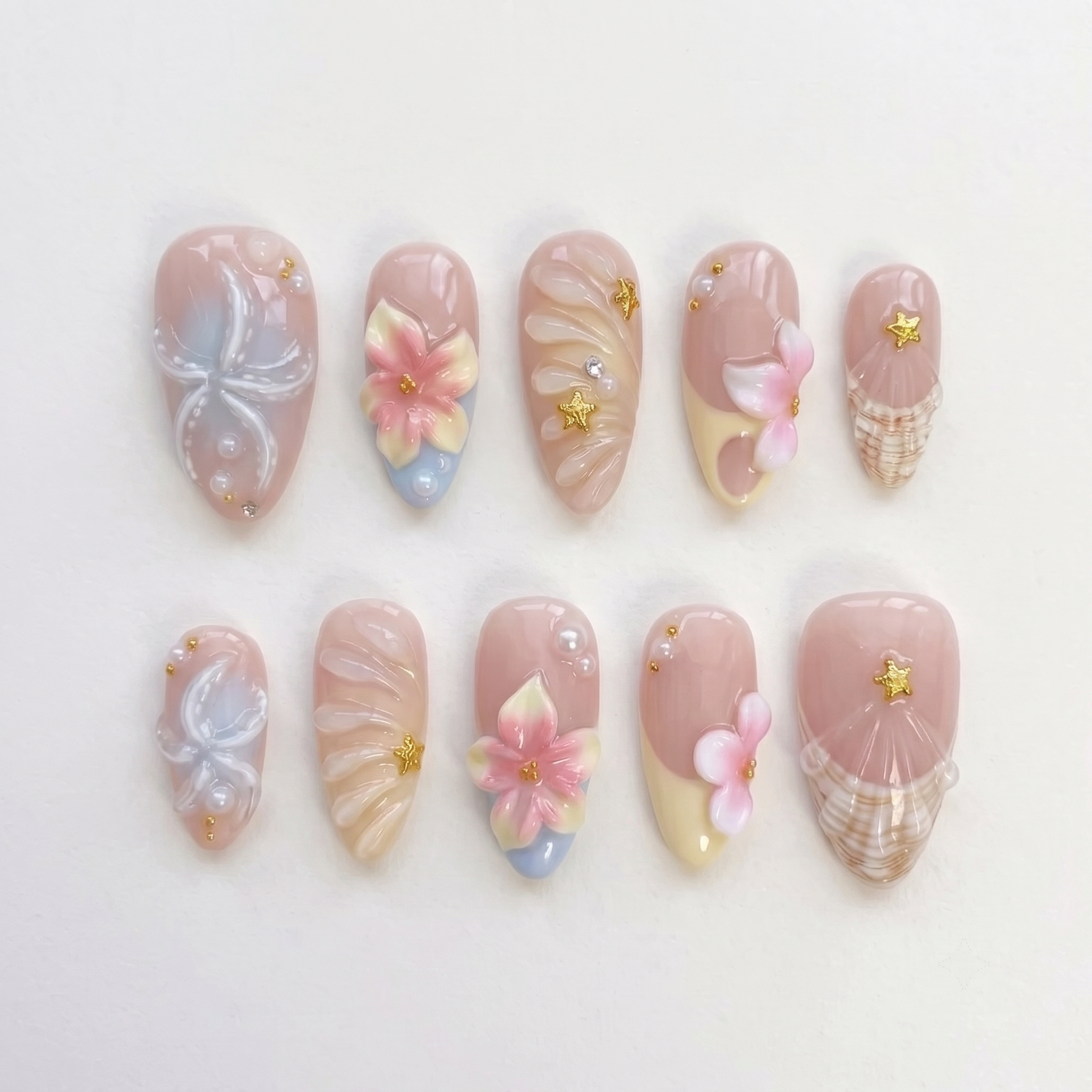 A set of pink press-on nails featuring 3D flowers, starfish, seashells, pearls, and gold star details.