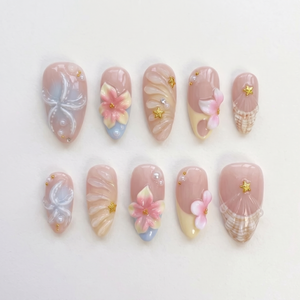 A set of pink press-on nails featuring 3D flowers, starfish, seashells, pearls, and gold star details.
