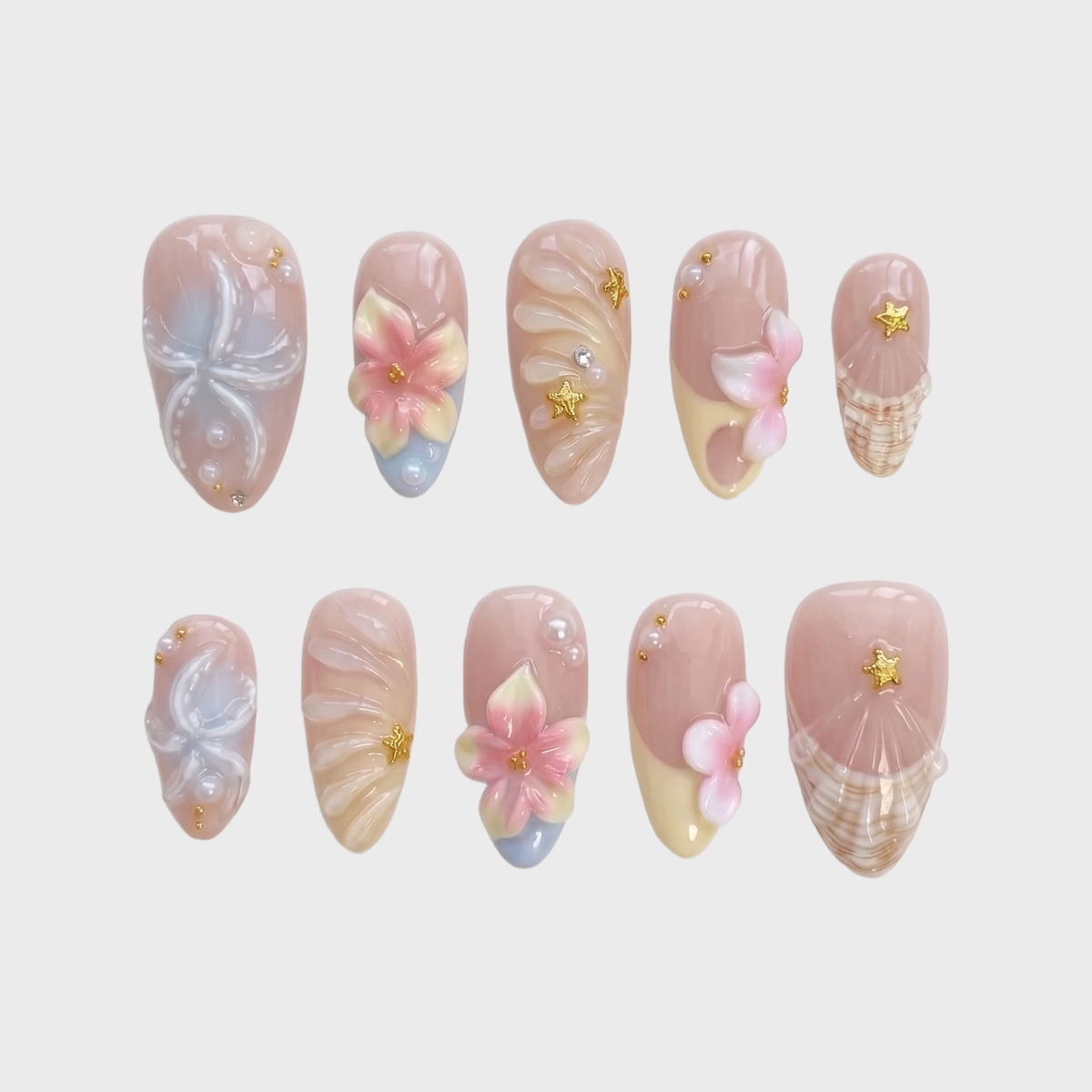 A set of pink press-on nails featuring 3D flowers, starfish, seashells, pearls, and gold star details.